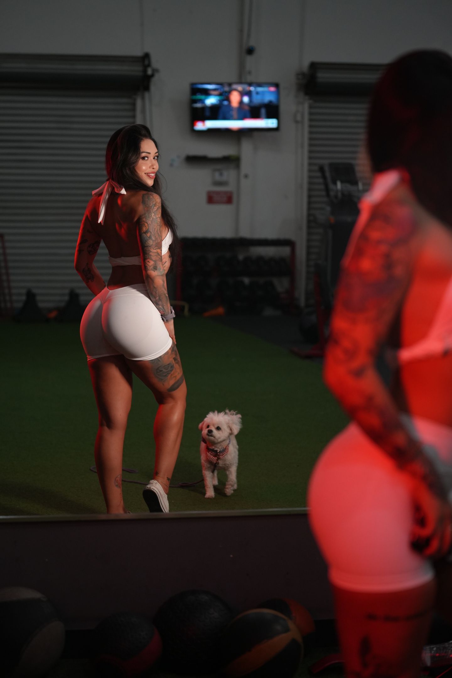 The coach crouches outdoors with her small white dog.