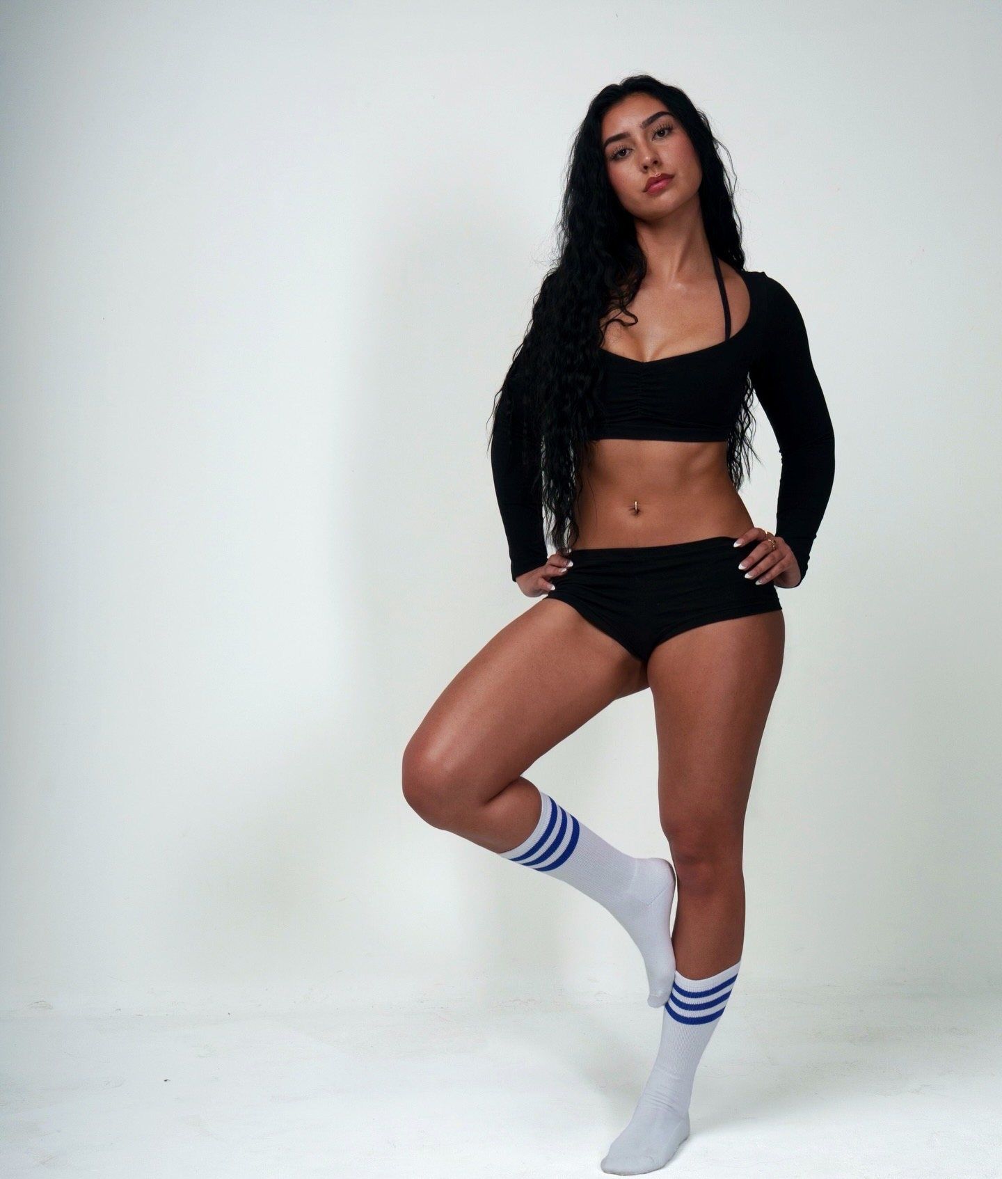 Claire standing with her hands on her hips in a black crop top and striped socks