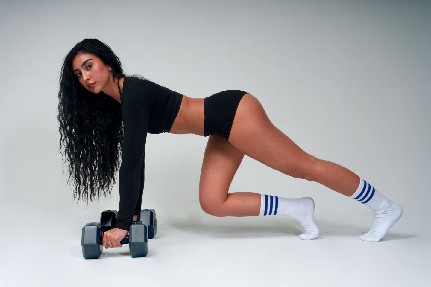 Claire in a plank position gripping two dumbbells